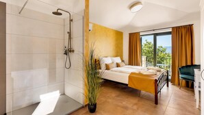 Ein modernes Schlafzimmer mit einem großen Bett, einer Dusche und Blick ins Freie.