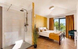A modern bedroom with a large bed, a shower, and a view of the outdoors. - Amazing home in Vrbnik with sauna (Vrbnik)