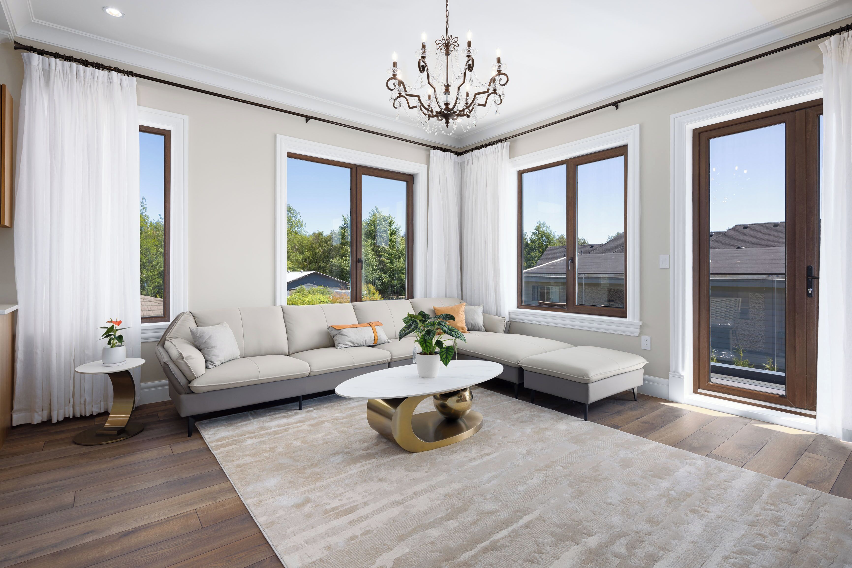 A spacious living room with a large sectional sofa, a round coffee table, and a chandelier.
