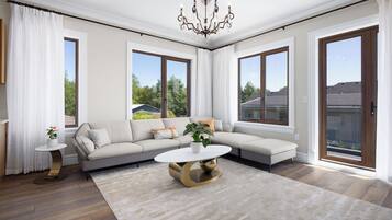 A spacious living room with a large sectional sofa, a round coffee table, and a chandelier.