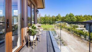 Une maison moderne avec une porte vitrée donnant sur un balcon aménagé avec du mobilier d’extérieur et un pot de fleurs.