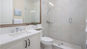 Une salle de bain moderne avec une douche à parois de verre, un lavabo blanc et des toilettes.