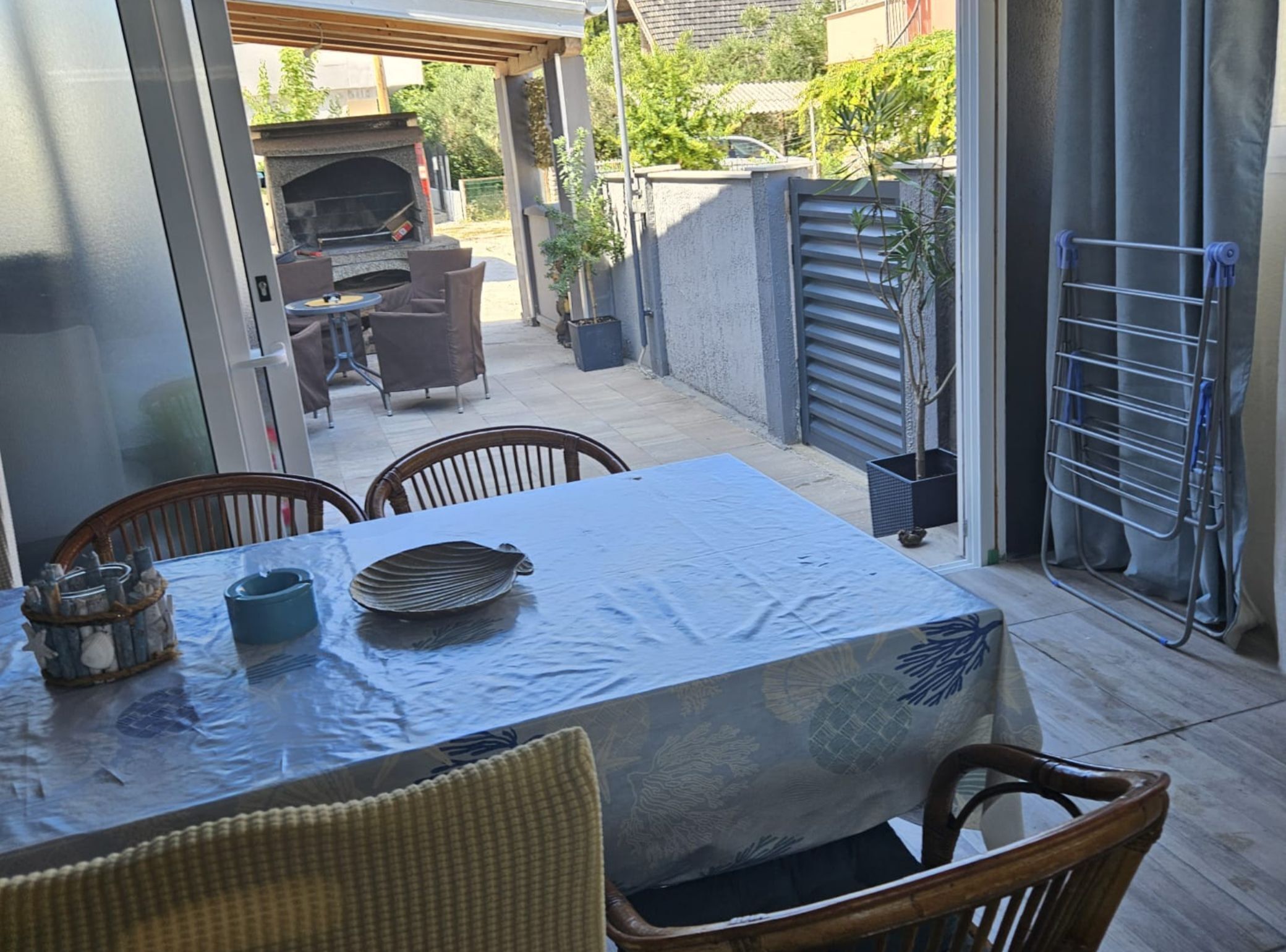A patio with a table and chairs, a grill, and a drying rack.