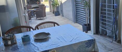 A patio with a table and chairs, a grill, and a drying rack.