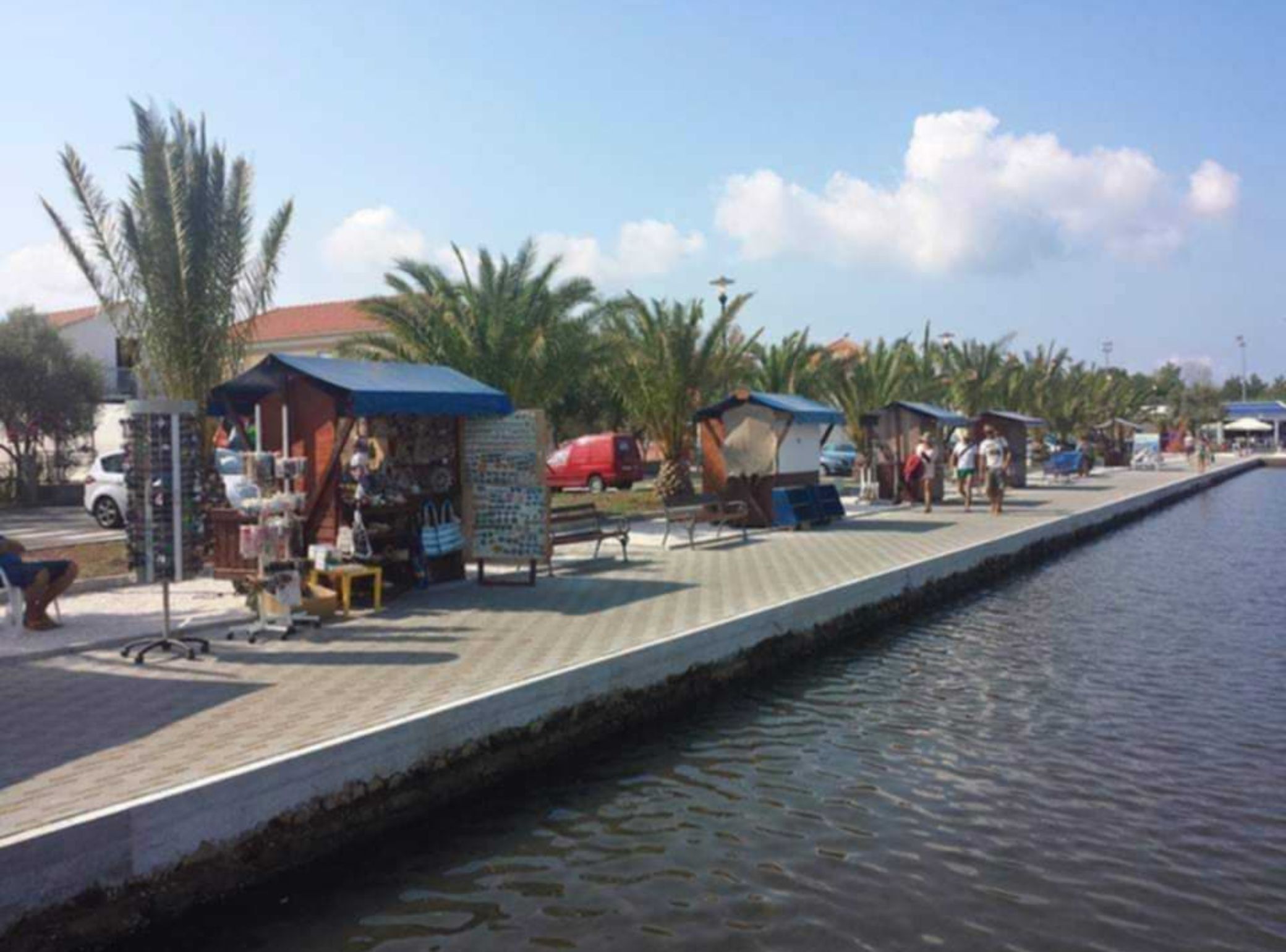 A waterfront promenade with small kiosks and benches along the edge.
