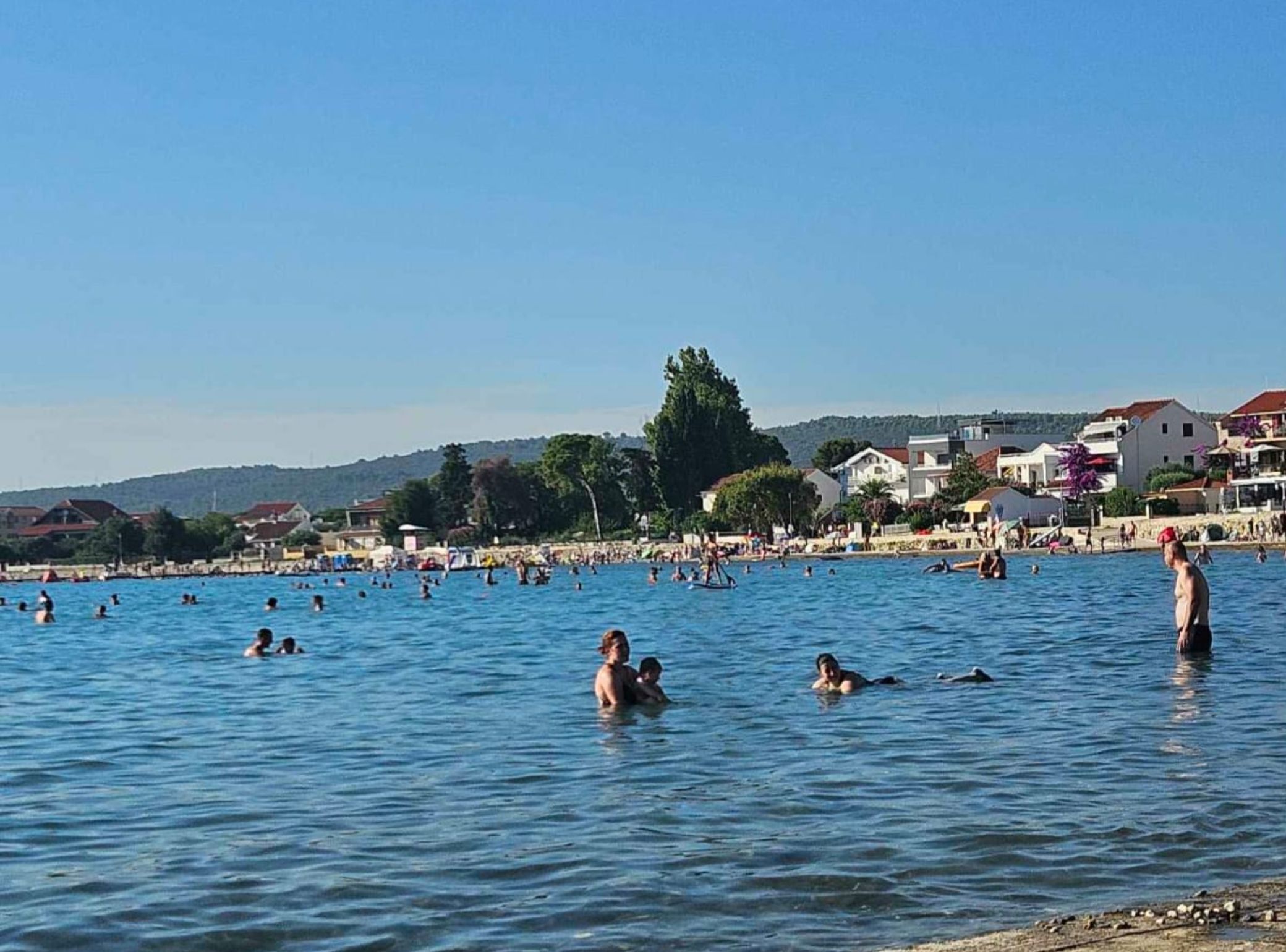 A coastal area with people swimming and sunbathing.