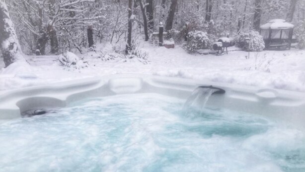 A hot tub surrounded by snow-covered trees and a gazebo. - Golden Spa Suite (Port Franks)