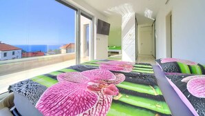 A modern hotel room with a balcony, large windows, and a bed with floral bedding.