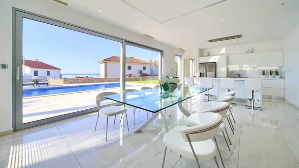 A modern kitchen with white cabinets and a glass dining table.