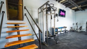 Un gimnasio con escalones de madera, equipamiento de halterofilia y un letrero de neón.