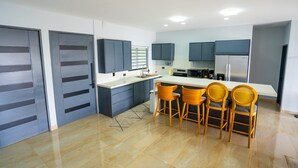 Una cocina moderna con armarios grises, encimera blanca y una isla central con taburetes de bar.