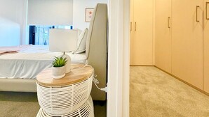 Ein modernes Schlafzimmer mit Bett, Nachttisch, Lampe und Kleiderschrank.