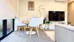 Ein modernes Wohnzimmer mit Essbereich, einem Flachbildfernseher und einem großen Fenster.