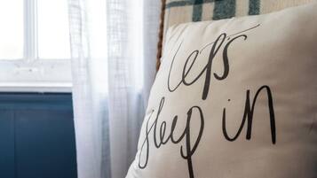 A pillow with the text "Let's sleep in" on a bed.
