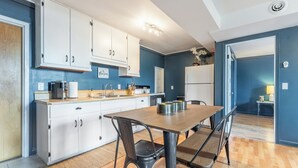 A modern kitchen with white cabinets, a wooden dining table, and a kitchen island. - The Mason Apartment-Cozy Getaway (Livingston)