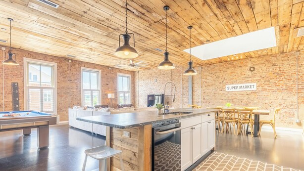A spacious living area with a pool table, a kitchen island with a dishwasher, and a dining area with a table and chairs.