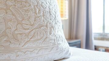 A close-up of a white, intricately embroidered pillow on a bed.