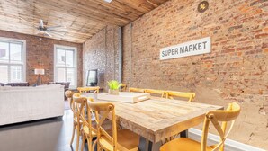 A dining area with a wooden table and chairs, a brick wall, and a 'Super Market' sign.