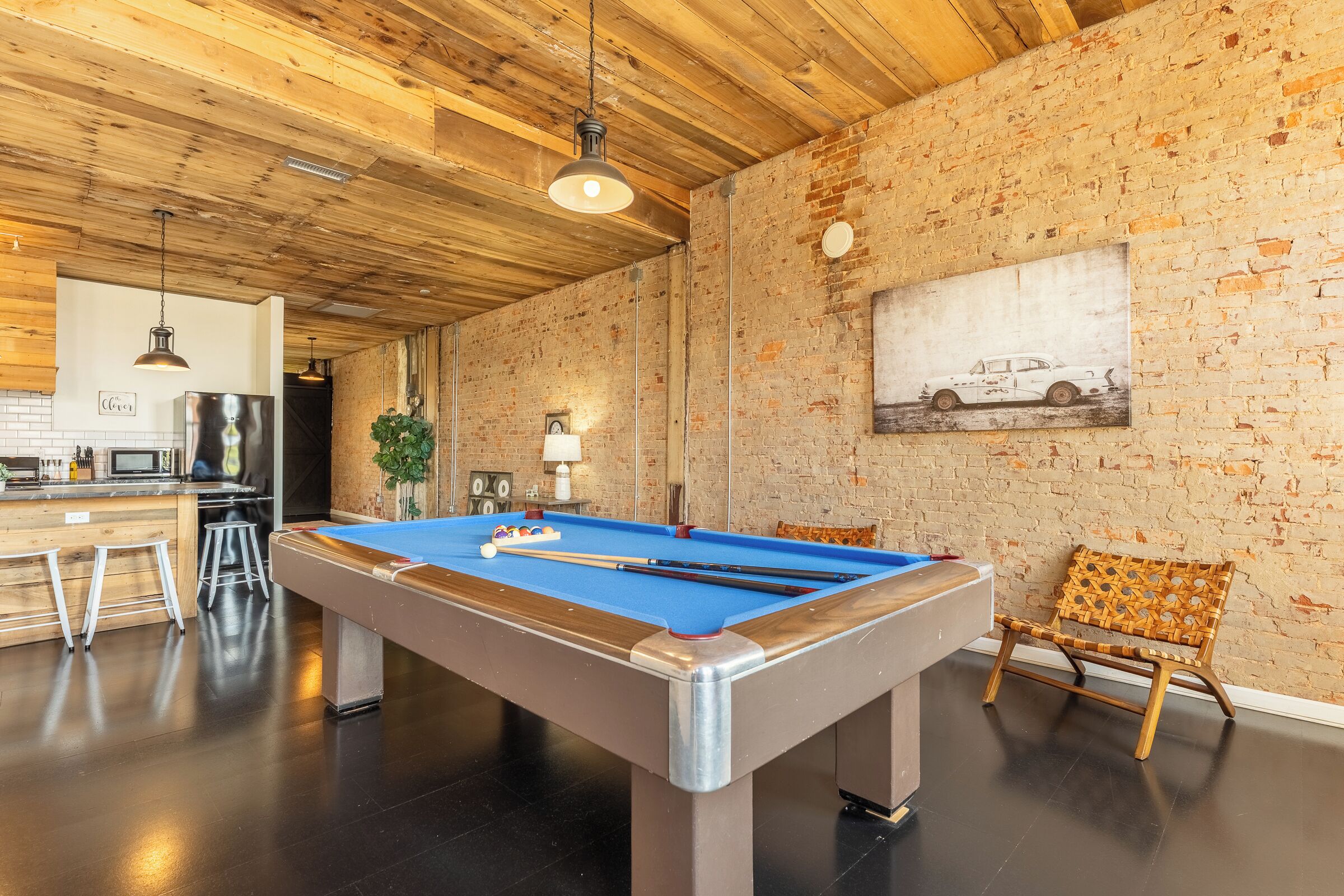 A pool table in a room with a brick wall and wooden ceiling.