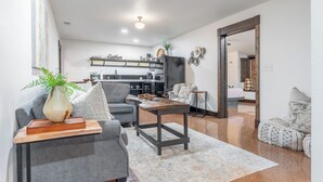 Una sala de estar moderna con un sofá gris, una mesa de centro y una cocina al fondo.