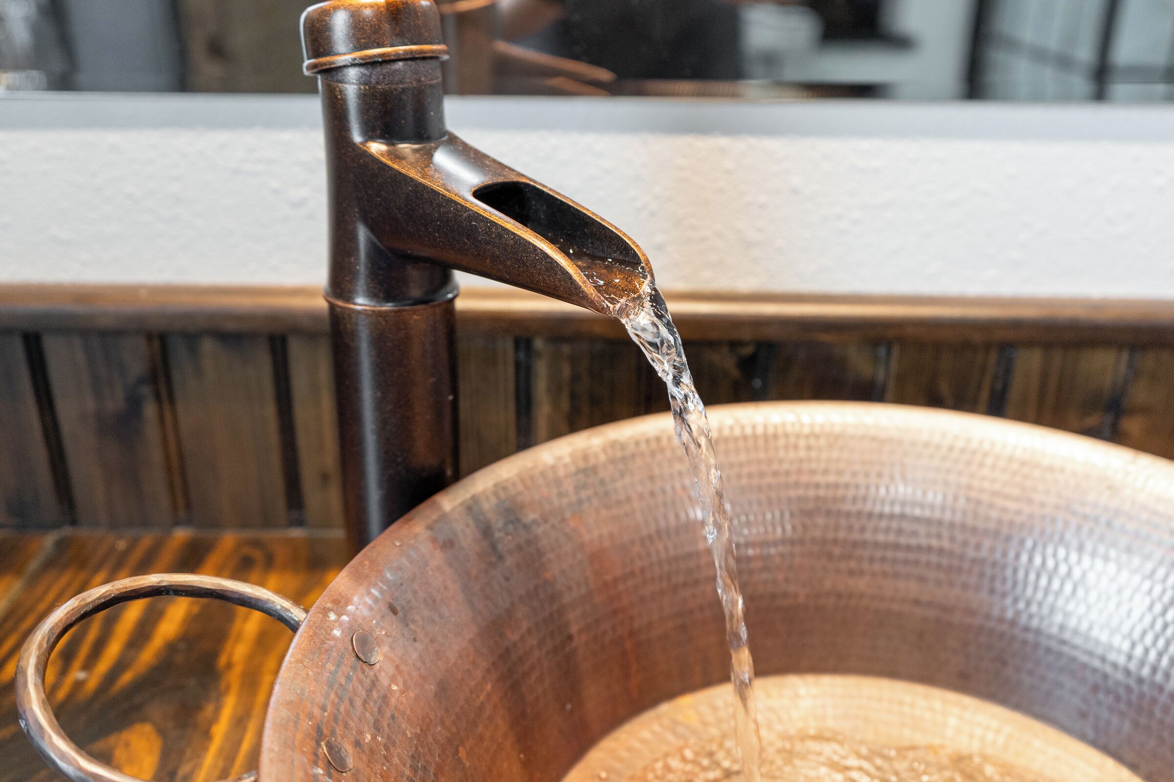 Un bol en bois placé sous un robinet, l’eau s’y écoulant.
