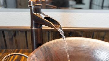 Un bol en bois placé sous un robinet, l’eau s’y écoulant.