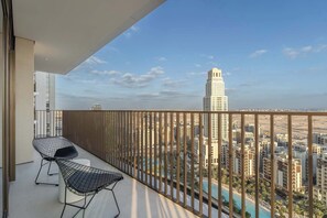 A balcony with two wireframe chairs, a view of a cityscape with tall buildings, and a swimming pool. - A Free Housekeeping Visit FOR Every Stay Between THE 16th FEB AND THE 16th MAR - Stayshort - Luxury 3 Bedroom in Dubai Creek Harbour That Sleeps 6 (Dubai)
