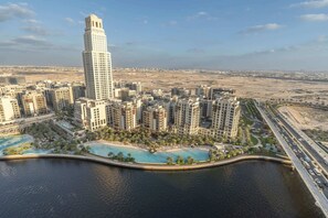 A high-rise building with a modern design, surrounded by other residential buildings, a large body of water, and a busy road. - A Free Housekeeping Visit FOR Every Stay Between THE 16th FEB AND THE 16th MAR - Stayshort - Luxury 3 Bedroom in Dubai Creek Harbour That Sleeps 6 (Dubai)