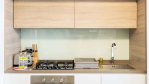 Een moderne keuken met houten kastjes, een gasfornuis, een spoelbak en een aanrecht met keukengerei en apparaten.