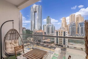 Ein Balkon mit einer Hängematte, einer Holzbank und Blick auf eine Skyline mit hohen Gebäuden.