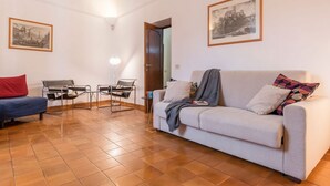A living room with a sofa, a chair, a small table, and two framed pictures on the wall. - Casa dell'Arco - WelcometoRhome (Roma)