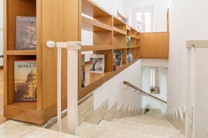 Een trap met houten planken vol boeken en een poster van een gebouw.