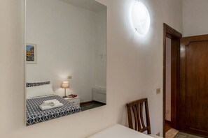 A bedroom with a bed, bedside table, lamp, and a mirror. - Casa dell'Arco - WelcometoRhome (Roma)