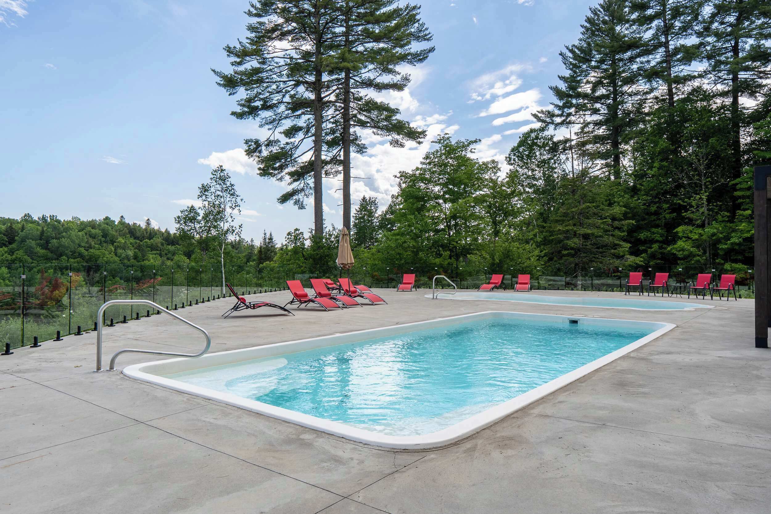 A swimming pool with red chairs and a metal ladder.