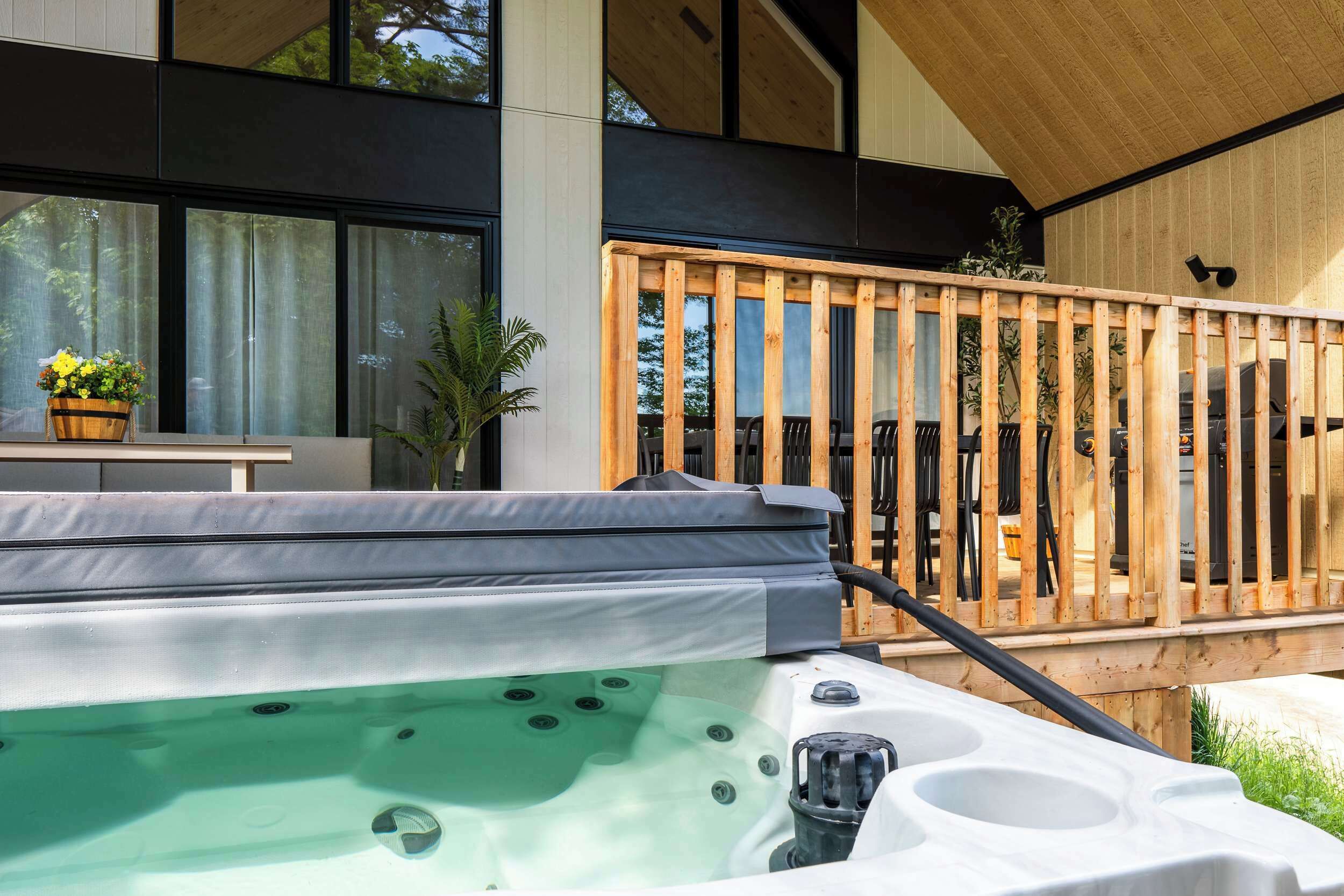 Un jacuzzi con cubierta de madera y un edificio moderno al fondo.