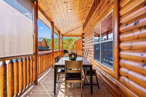 Eine Holzhütte mit überdachter Veranda, einem Esstisch und Stühlen.