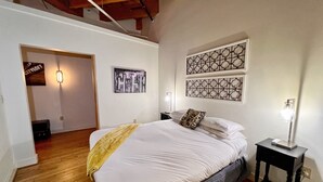 Ein Schlafzimmer mit einem Bett, einem Nachttisch, einer Lampe und einer Wand mit zwei dekorativen Paneelen.