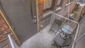 Ein Balkon mit Metallgeländer, einer Tür und einer Ziegelwand.