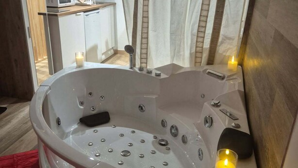 A modern bathroom with a freestanding bathtub, a vanity with a mirror, and a small seating area. - Romantic room (Les Arcs)