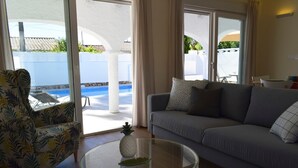 A living room with a sofa, a glass coffee table with a pineapple, and a view of a pool through large sliding glass doors. - 05 Ch3200 in Denia With 3 Bedrooms and 2 Bathrooms (Denia)