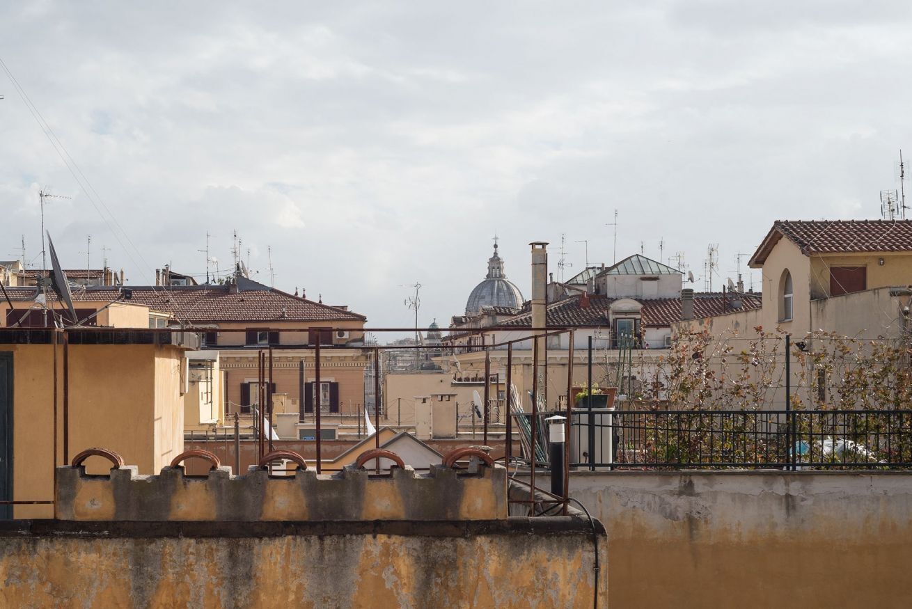 A view of a cityscape with buildings, a dome structure, and a fence.