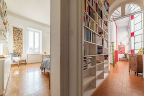 A spacious room with a large bookshelf, a window, and a cozy seating area. - Casa di Cosimo - WelcometoRhome  (Roma)