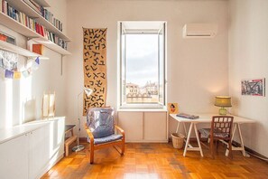 A room with a window, a desk, two chairs, a bookshelf, and a wall-mounted air conditioner. - Casa di Cosimo - WelcometoRhome  (Roma)