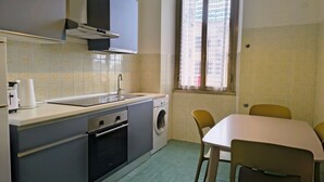 Eine kleine Küche mit Waschmaschine, Spüle und einem Fenster mit Blick auf Gebäude.