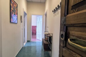 A narrow hallway with a tiled floor, a door with a metal handle, and a wall-mounted rack with items. - Casa di Vigo - WelcometoRhome (Rome)