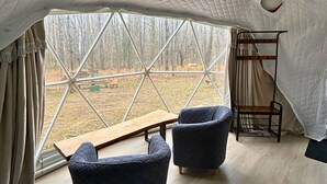 A cozy interior with a large window, two upholstered chairs, a wooden bench, and a metal rack. - Dome & Private Sauna - Poplar Palace - 100 acres (Augusta)