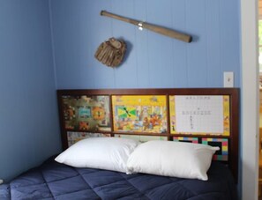 A bedroom with a bed, a headboard with a bulletin board, and a wooden stick on the wall. - Cabin 5 at Dockside Lake Resort (Monticello)