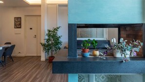 Een moderne keuken met een donker aanrecht, potplanten en een zichtbare deur naar een andere kamer.