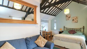 Een slaapkamer met een bed, een sofa, een houten plafond, een spiegel en een raam.