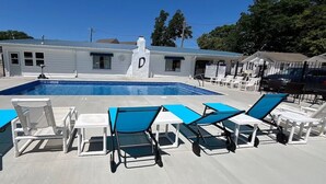 A swimming pool area with lounge chairs and a building with a 'D' logo. - Motel 10 at Dockside Lake Resort (Monticello)
